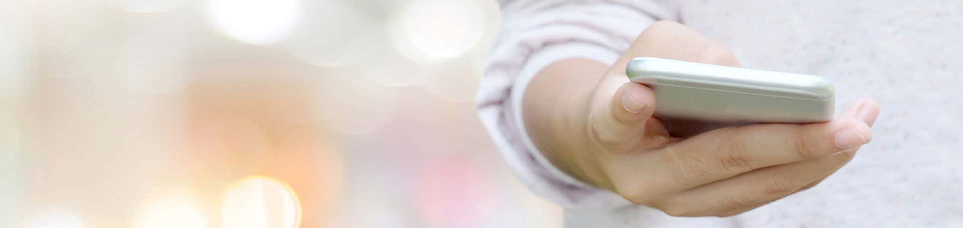 Main à l'aide de téléphone intelligent sur fond clair flou